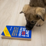 κουταβάκι δαγκώνει ένα βιβλίο σχετικό με την εκπαίδευση σκύλων