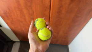 ανρώπινο χέρι κρατάει δύο μικρά μπαλάκια του τέννις